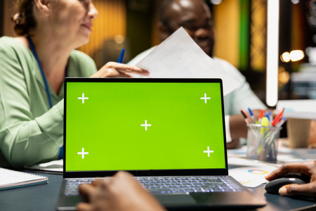 Company associates briefing after hours next to chroma key screen, experts group exchanging insight with files and establish project objectives. Performance summary for goals presentations.の写真素材