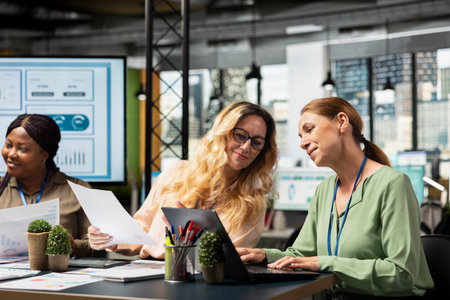 Multiethnic businesswomen group working on development plans and strategic thinking together in office space, reflecting visionary objectives alignment in business environment.の写真素材