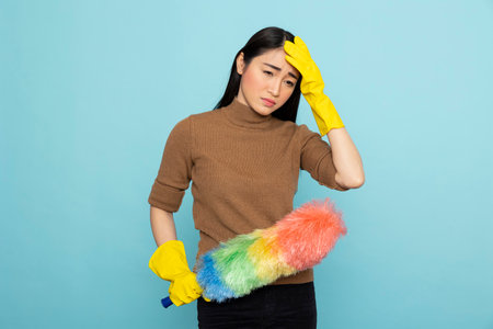 Portrait of overwhelmed cleaning service staff holding feather duster, experiencing job fatigue....