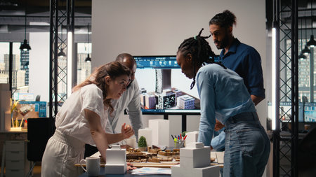 Close up of developers arranging 3D models to explore residential layout options, working on structural city planning for urban development project during a strategic team meeting.の写真素材