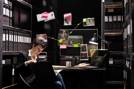 Woman law officer working on criminal investigation in evidence room, reviewing case files and clues authenticity while uncovering new forensic details. Finding proof of organized crime.の写真素材