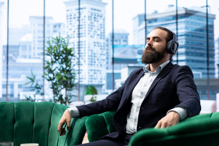 Director pauses for a moment of calmness listening to meditation sounds through his headphones, self care at the office. Mindfulness essential for leadership and global business success.の写真素材