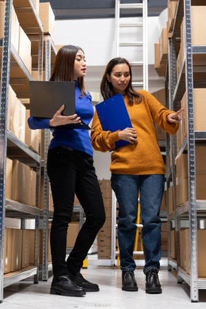 Asian staff members hand packing parcels and managing goods as startup warehouse operations. Local delivery services and fulfillment processes essential to small business logistics.の写真素材