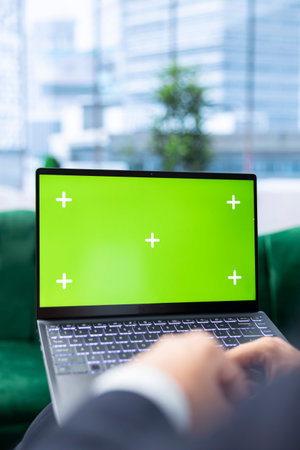 Determined entrepreneur uses laptop with copy space screen, tracking profit margins and making data driven decisions. Young businessman working on his success story, multitasking.の写真素材