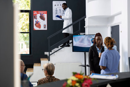 Medical professionals engaging in peer discussion and work communication in lobby at the hospital,...
