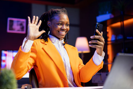 Smiling person in home office filming onboarding video with phone for job candidates, welcoming...