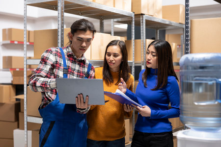 Asian employees group processing goods in packages for retail shipment, applies labels to boxes for...
