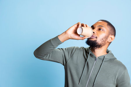 African american casual person relaxing with a fresh cup of coffee in studio, serving his hot...