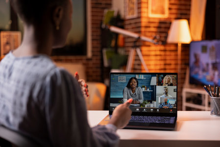 Professional woman participating in virtual meeting after sunset, collaborating with multiethnic...