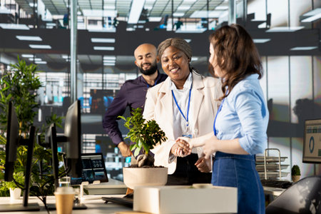 Diverse business people greeting their new colleague at the office, shaking hands when she enters...