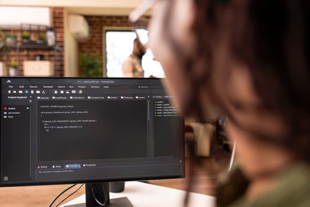 Closeup of black freelance developer using desktop pc to debug and refine website code. Rearview of...
