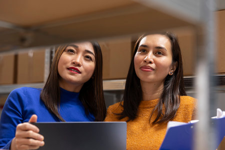 Small scale warehouse operations led by asian workers in a distribution hub. Packed orders in boxes waiting to be shipped from a local storehouse focused on express delivery service.の写真素材