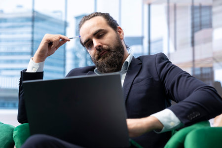 Young man entrepreneur reflecting about business success and innovation, thinking about the role of technology and digital transformation in driving company growth. Considering ideas.の写真素材