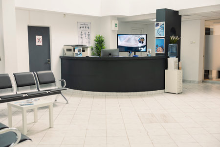 Modern hospital lobby with empty seats for patients and families awaiting appointments or consultations. Vacant front desk and waiting room in medical diagnostic clinic setting.の写真素材
