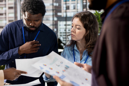 Administrator reviewing objectives data in a briefing meeting with the team, ensuring performance metrics in a modern corporation. Diverse staff members brainstorming new growth ideas.の写真素材