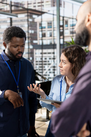 Diverse corporate staff gathered to brainstorm solutions together in the office, working to review reports for business growth. Workmates meeting and sharing insight on a successful strategy.の写真素材