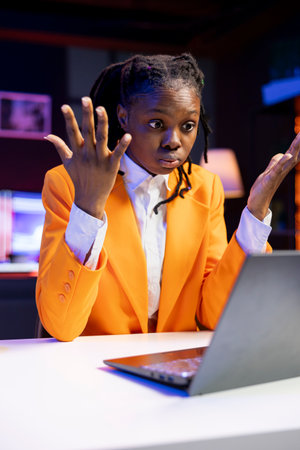 Frustrated manager working from home berating employee during videocall after finding mistakes in spreadsheets on laptop. Team leader in apartment office scolding worker during remote teleconferenceの写真素材