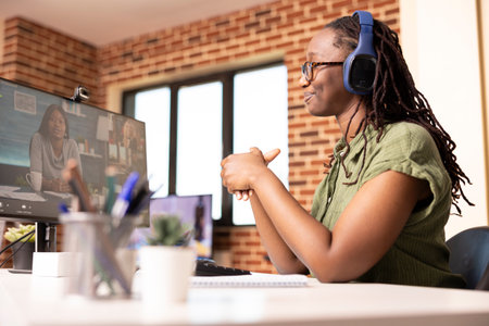 Focused african american remote worker using desktop pc to communicate with multiethnic team. Woman...