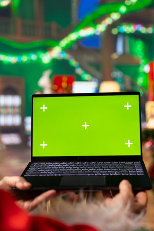 Close up of Santa Claus using mockup laptop to browse websites for upgraded sleigh accessories....