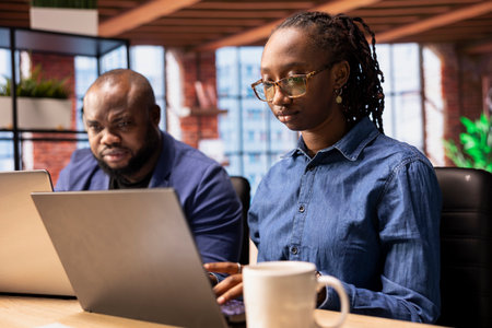African American people at their modern desk working on a freelance project, focusing on efficiency...