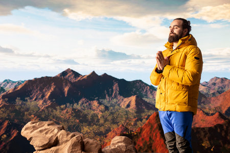 Pleased calm nature lover meditating on top of the mountain range, doing meditation poses and taking...