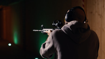 Shooting range customer shooting targets with semiautomatic weapon, having fun. Man at indoor...