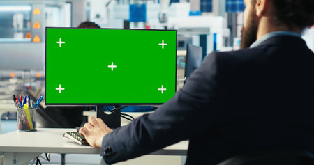 Photovoltaics factory worker uses green screen PC to monitor performance of robot arms manufacturing...