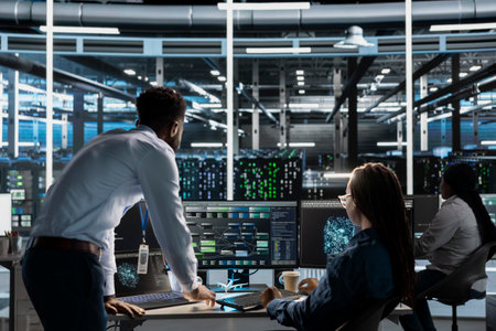 Data center manager supervises engineer using AI visual programming to optimize gear. Server farm...