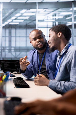 Data center admin discussing with coworker, using programming languages to construct algorithms and...