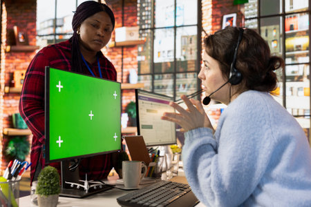 Call center onboarding specialist training new recruit using green screen computer. Supervisor in...