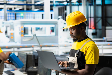 Photovoltaics facility supervisor using laptop for a test inspection, finetuning the production process. Male worker improving solar panel configurations for eco friendly renewable energy.の写真素材