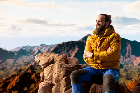 Hiker traveler pauses to admire the panoramic mountain scenery on the hill top, endless sky and...