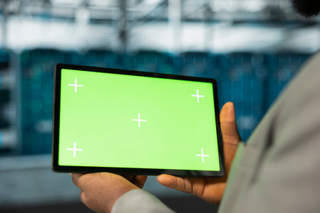Close up of data center engineer using green screen tablet in data center, performing maintenance on...