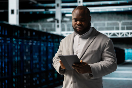 Data center employee fixing network issues affecting rigs performance, scripting automated workflows. Technician running system diagnostic tests, evaluating reports on tabletの写真素材