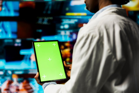 Doctor monitoring medical research data and 3D anatomy models dashboards with green screen mockup tablet. Clinician using chroma key device to project visual medical reports on multimedia wallの写真素材