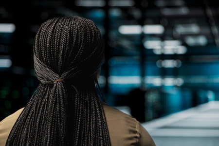 IT specialist walks in high tech data center with rigs supporting business needs. Server room staff member does checkup, ensuring equipment rackmounts work at optimum performance for smooth operationsの写真素材