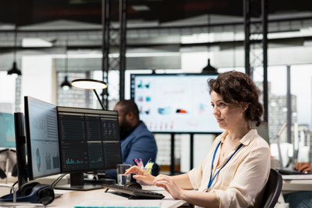 Female office worker uses digital tech to examine business resources and performance metrics in a multinational company corporate space. Leveraging data insights for efficiency.の写真素材