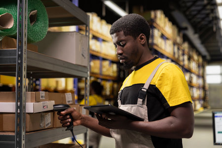 African american man using a barcode scanner to process shipping labels on boxes from industrial storage racks. Scanning awb tags for package tracking service with tracking info, accurate logistics.の写真素材