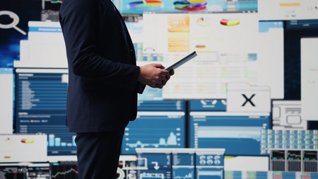 Professional businessman analyzing info and finance charts on digital dashboard, ensuring strategic planning with infographics on tablet. Leadership in fast paced corporate economy. Camera B.の写真素材