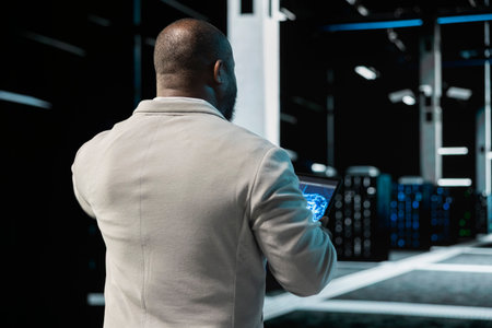Data center engineer using AI technology on tablet to enhance operational effectiveness. Server hub...