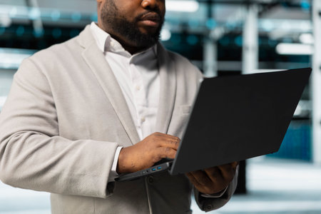 Close up of engineer in server hub checking recovery plan on laptop, monitoring hardware energy...
