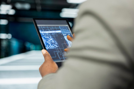Close up of data center developer using AI software on tablet to monitor equipment energy...