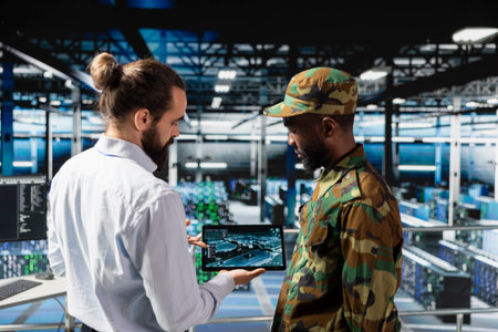 Military server room IT professionals using AI LLM tech on laptop to review network performance. Army operators managing hardware systems supporting armed forces mission for national security.の写真素材