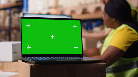 Logistics employee organizing packages near isolated mockup on computer, inserting order tracking tools and labeling systems. Staff member analyzing business inventory dashboards. Camera B.の写真素材