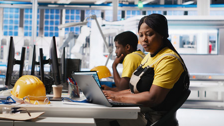 Black woman technician testing solar panel designs on industrial software, working in alternative energy manufacturing plant. Female engineer optimizing the production line. Camera A.の写真素材