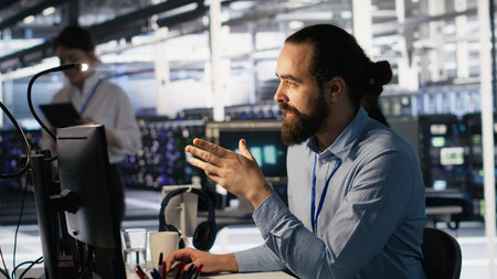 Data center technician discussing with coworker while doing AI software updates. Server room IT specialist and colleague chatting, optimizing infrastructure using artificial intelligence, camera Aの写真素材