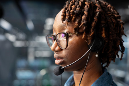 Close up of female technician on industrial platform speaks in headset mic, overseeing maintenance on AI server rigs below. Admin coordinates machine learning system operations.の写真素材