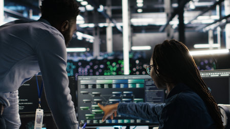 Data center manager supervising engineer using node tree tool to identify equipment performance issues. Server hub team leader talks with IT specialist reviewing data analysis graph, camera Bの写真素材