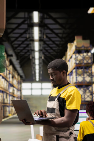 Warehouse technician inspecting cargo details on shelves in a large scale fulfillment center. Ensuring safety protocols followed with proper workwear. Logistics management and dispatch in action.の写真素材