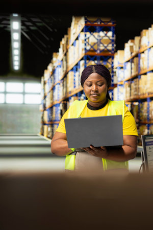 E-commerce business worker manages a shipping depot with packages ready for delivery. Staff handling inventory and performing quality control, local distribution across the region.の写真素材